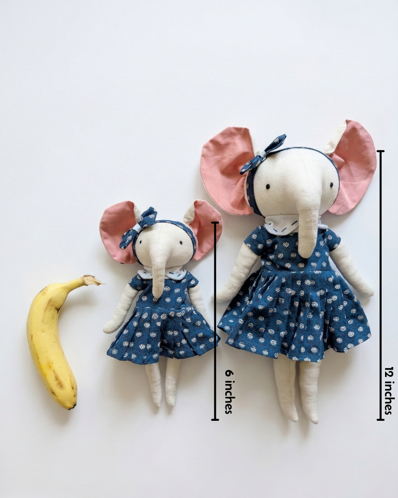 Two elephant-shaped dolls in blue floral dresses with a banana and measurements highlighted on a scale with white background