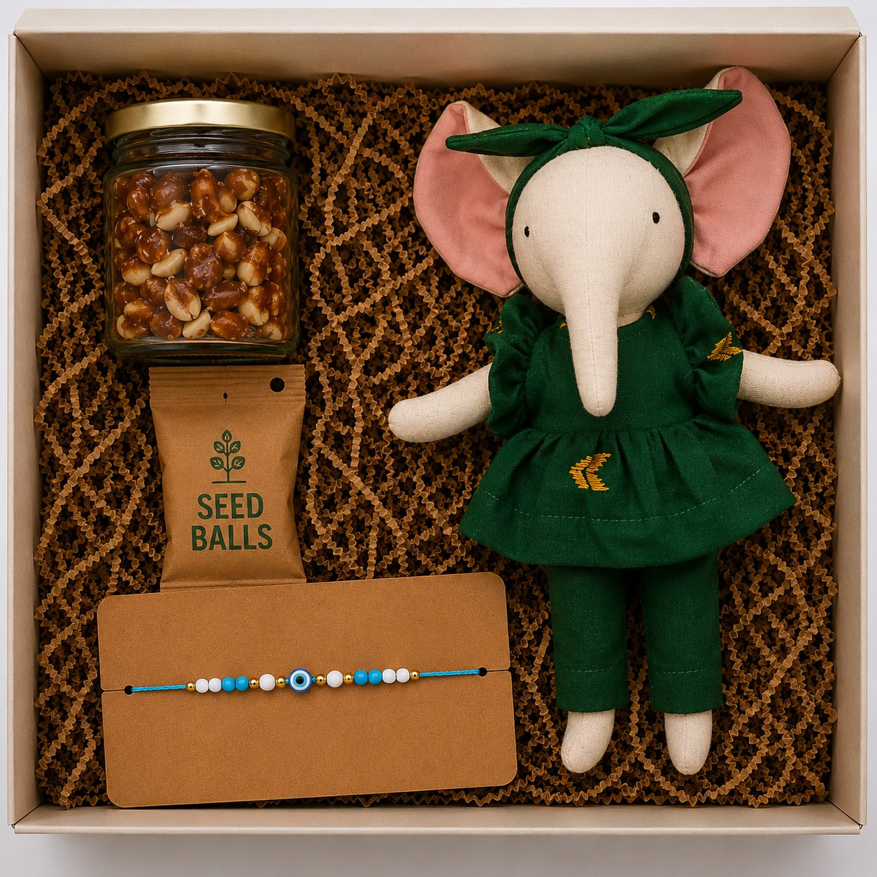 A rakhi gift hamper for kids, that includes a handmade elephant soft toy, seed ball, and home-made caramelized peanuts along with rakhi. 