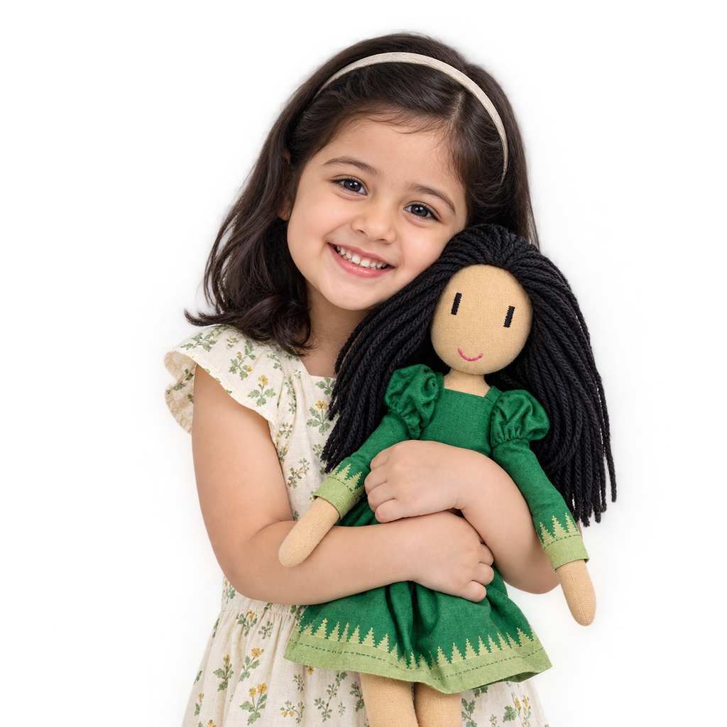 A young girl with dark hair and a white headband smiles while holding a wooden doll with long black yarn hair and a green dress, set against a solid white background.
