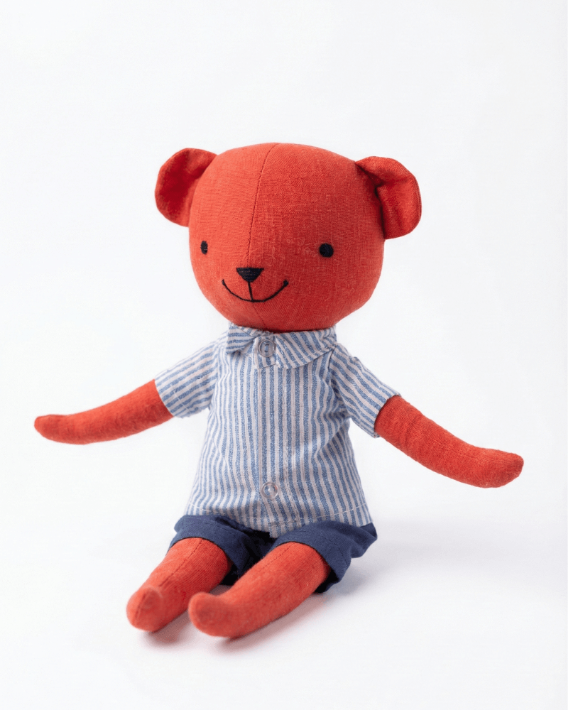 Red teddy bear wearing a striped shirt and shorts on a white background