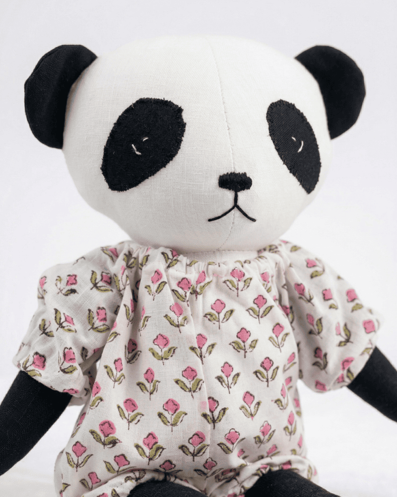 Close up panda soft toy wearing a floral dress on a white background