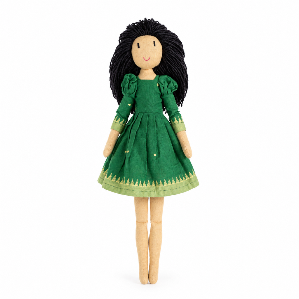A handmade wooden doll with long black yarn hair, wearing a green dress with gold trim, standing against a plain white background.